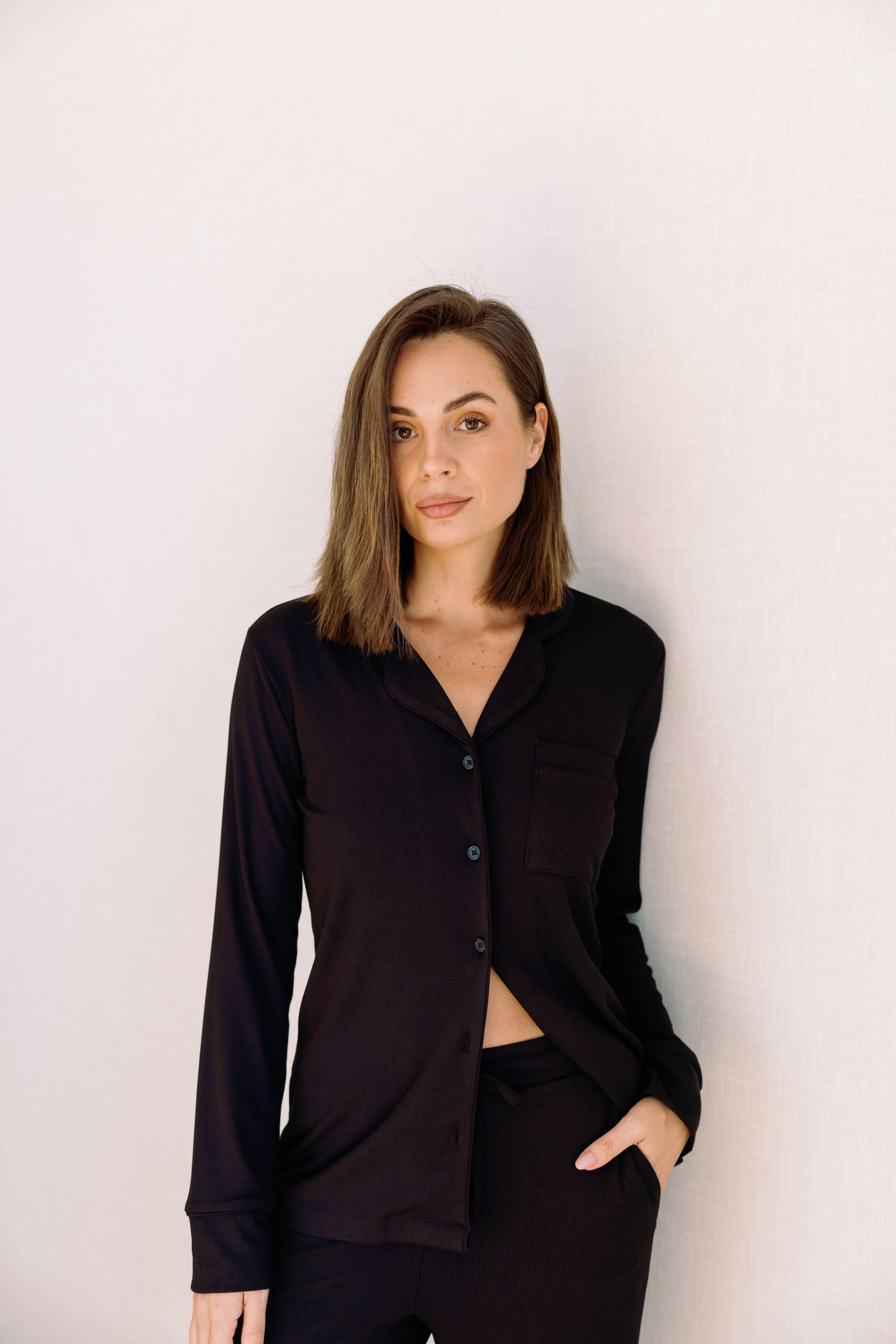 Woman wearing long ribbed modal pyjamas in black against white background